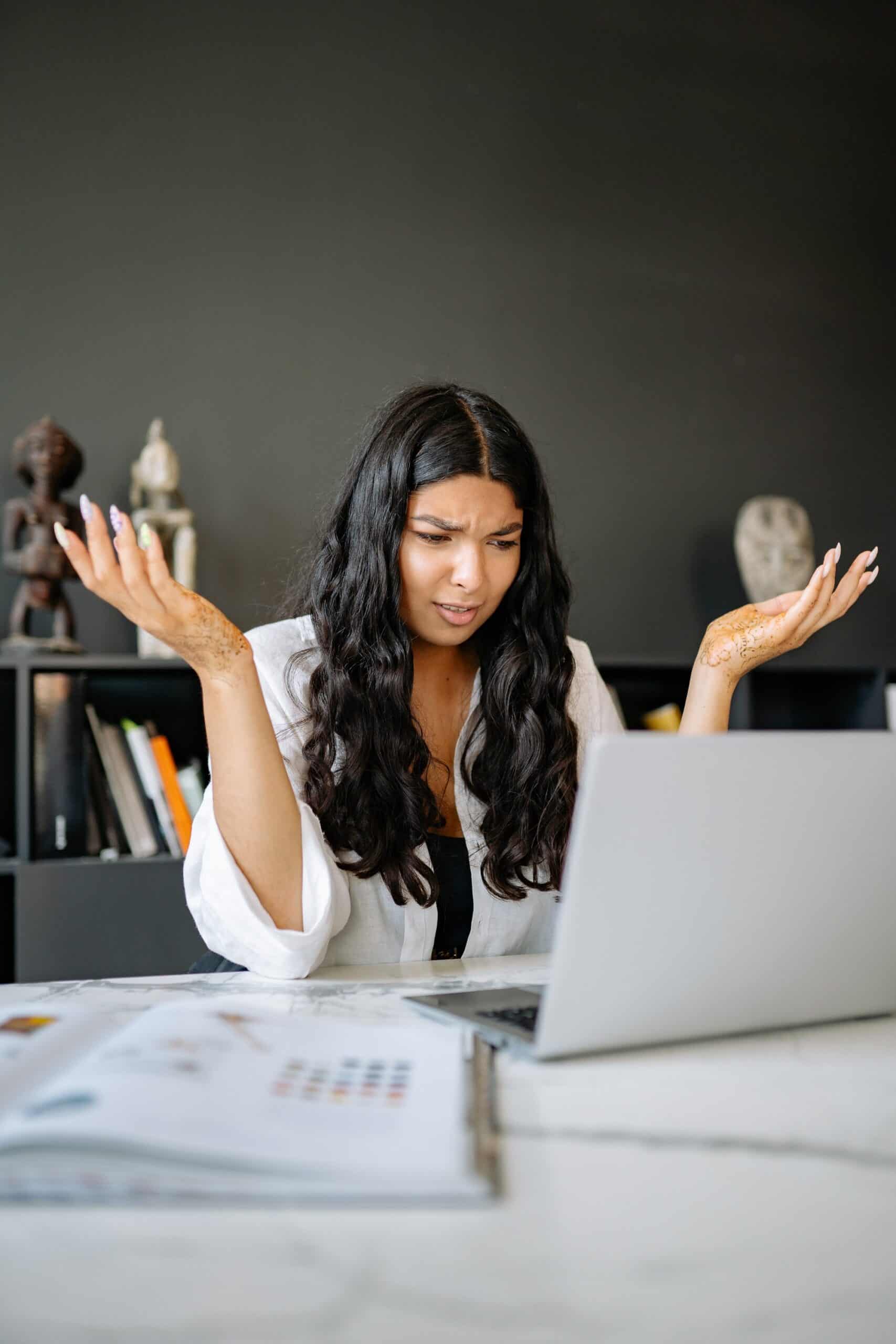 A confused young lady staring at her laptop trying to decide if she is to trade cryptocurrency or forex